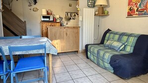 Un espacio habitable compacto con una mesa de comedor, sillas, sofá y una cocina con microondas, además de una escalera.