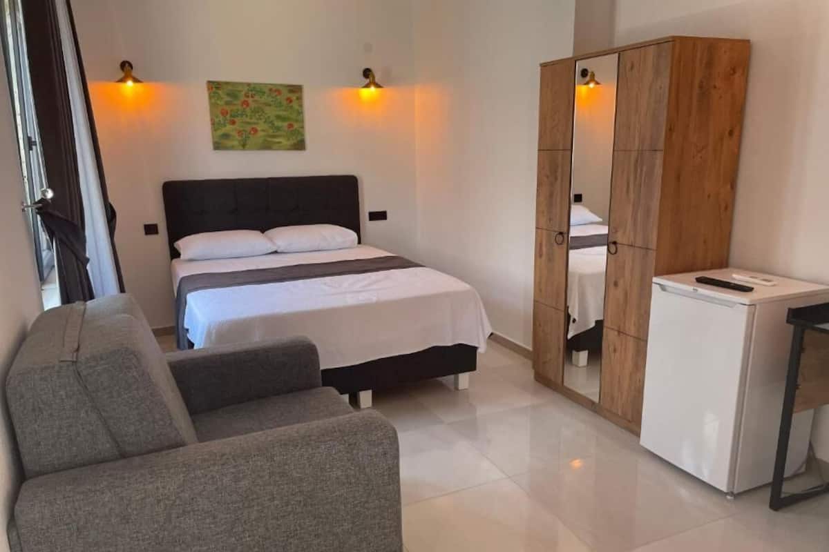 A bedroom with a bed, a wardrobe, a desk, and a chair.