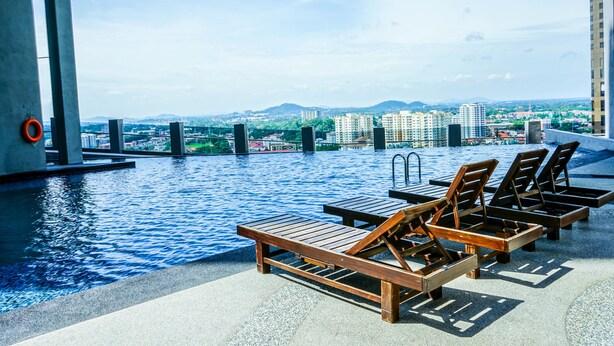 Zona de piscina en la azotea con sillones y vista panorámica de la ciudad.