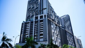 Un edificio de gran altura con diseño arquitectónico moderno, que cuenta con múltiples balcones y una estructura vertical destacada.