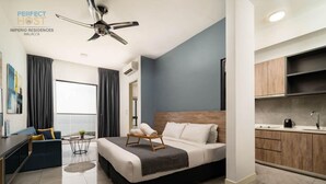 Una habitación de hotel moderna con cama, un pequeño rincón de descanso, kitchenette y un amplio ventanal.