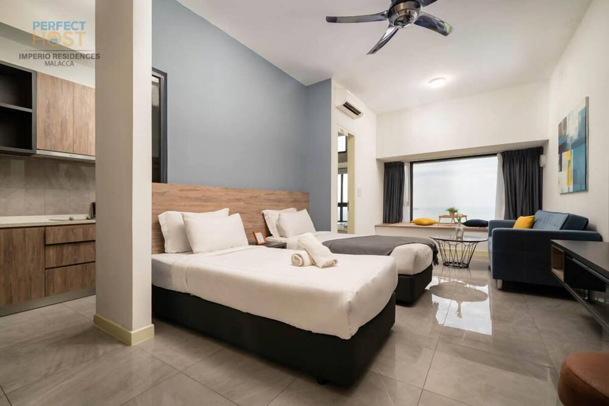 Quarto de hotel moderno com uma cama grande, uma escrivaninha, uma cadeira e vista para a cidade.