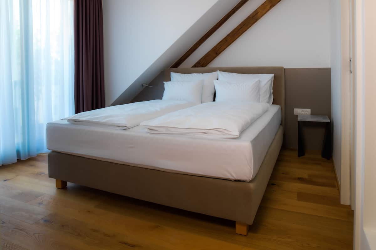 Une chambre moderne avec un grand lit, un plancher en bois et un plafond en pente.