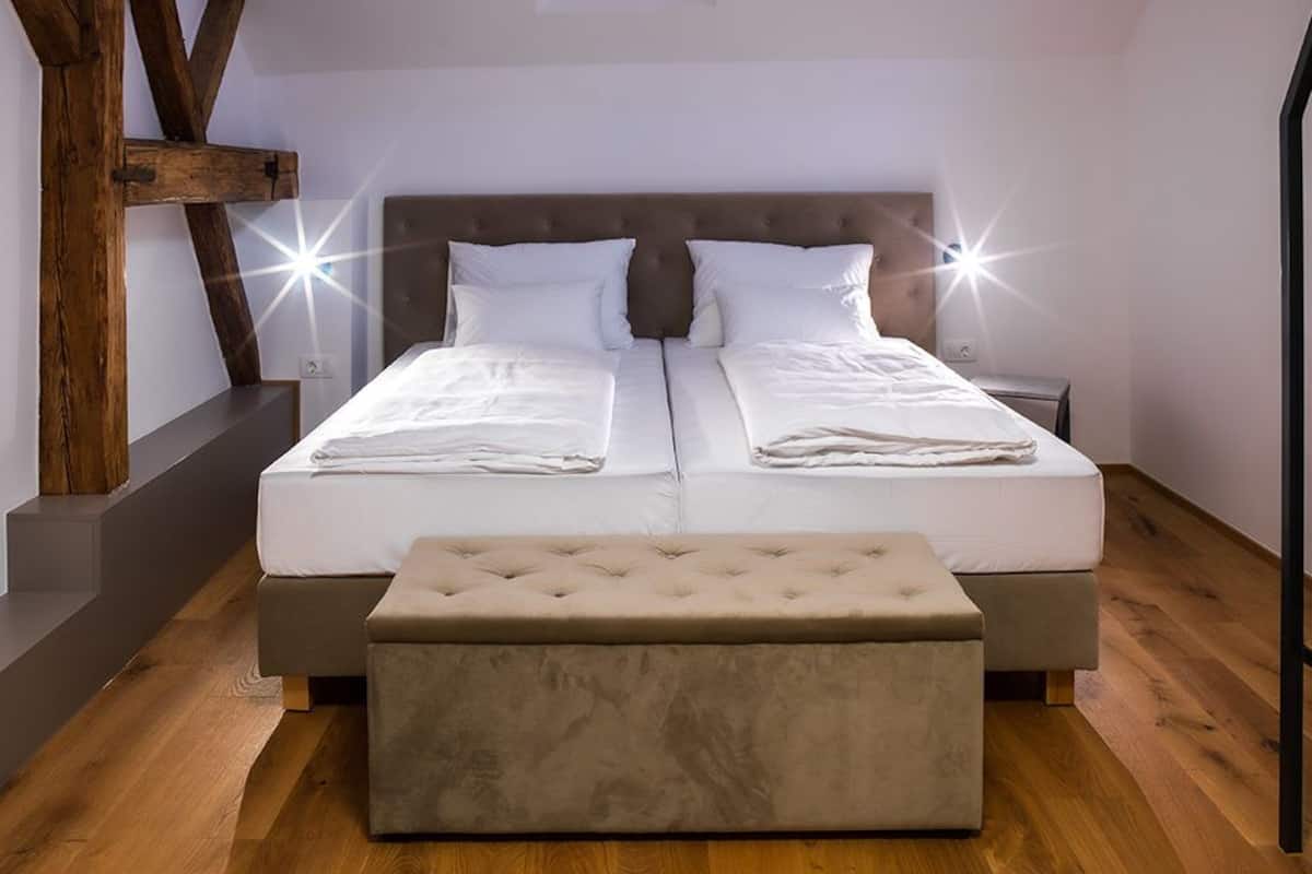 Une chambre à coucher avec un grand lit, un banc et une structure en poutres apparentes.