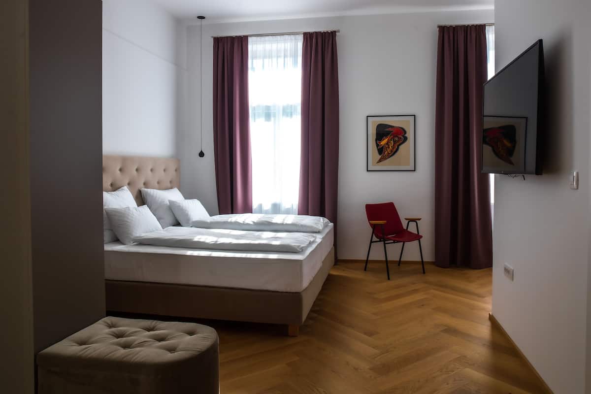 Une chambre à coucher avec un lit, une chaise et un téléviseur.