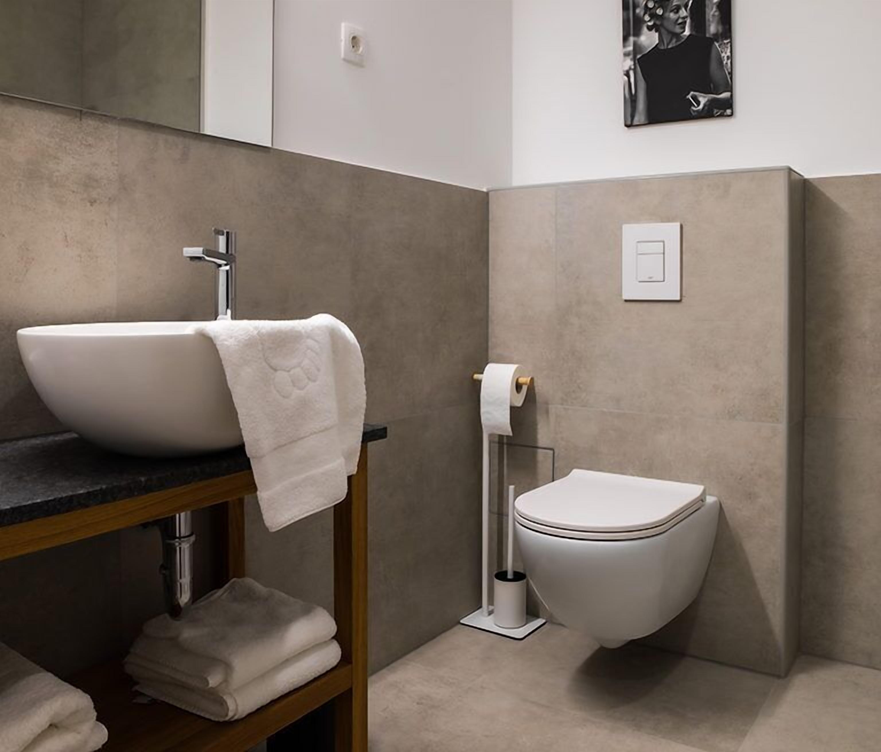 A modern bathroom with a large vessel sink, a toilet, and a towel rack.