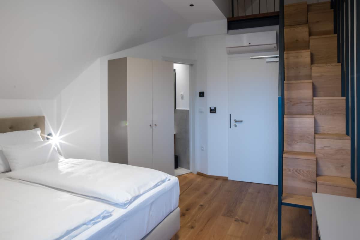 Une chambre à coucher avec un lit, un plancher en bois, une armoire et un escalier.