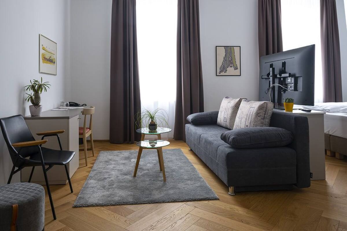 Un salon moderne avec un canapé gris, une petite table ronde et un tapis gris.