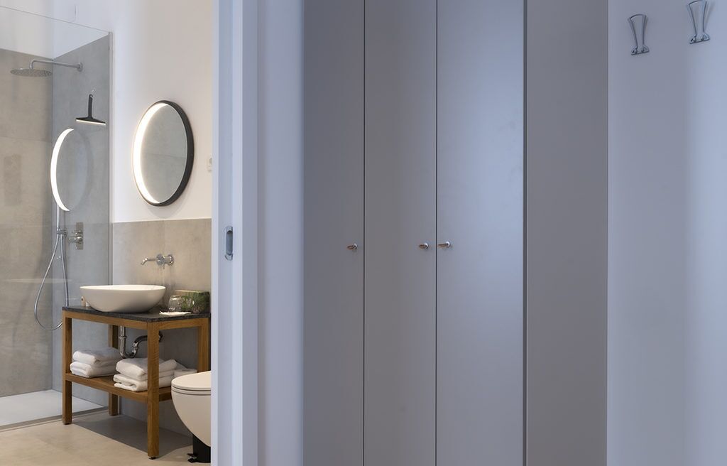 Un baño moderno con ducha de vidrio, tocador de madera con lavamanos y un inodoro.