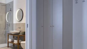 Un baño moderno con ducha de vidrio, tocador de madera con lavamanos y un inodoro.