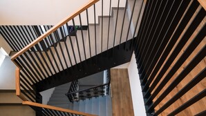 Een moderne trap met houten en metalen leuningen, die uitkomt op een plateau met een lamp.