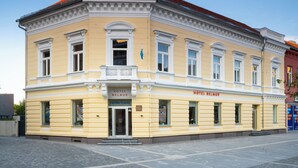Een historisch gebouw met een geel gevel, een bord waarop 