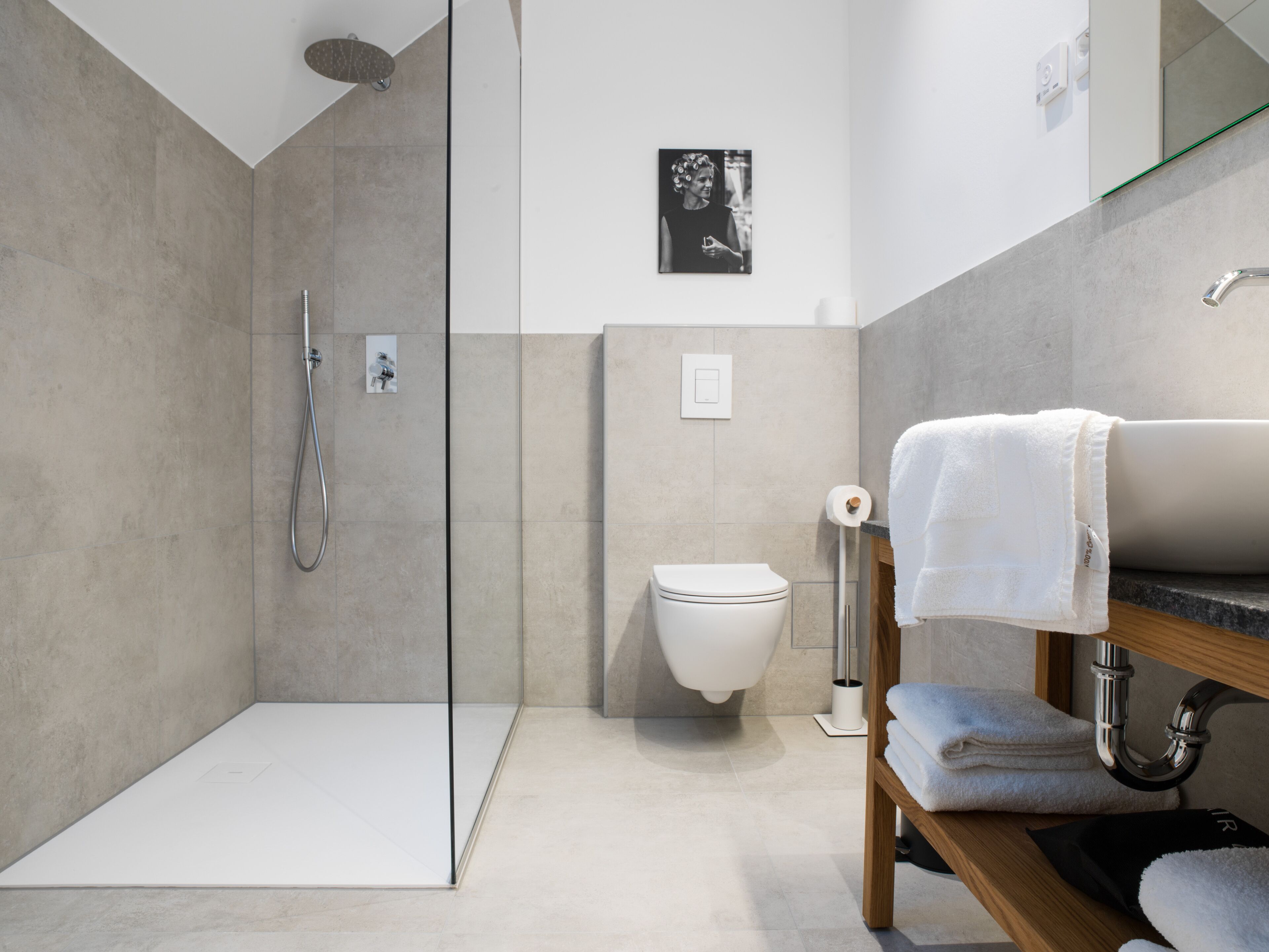 Une salle de bain moderne dotée d’une douche à parois de verre, de toilettes et d’un meuble-lavabo avec un porte-serviettes.
