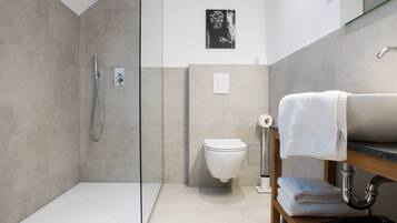 Une salle de bain moderne dotée d’une douche à parois de verre, de toilettes et d’un meuble-lavabo avec un porte-serviettes.
