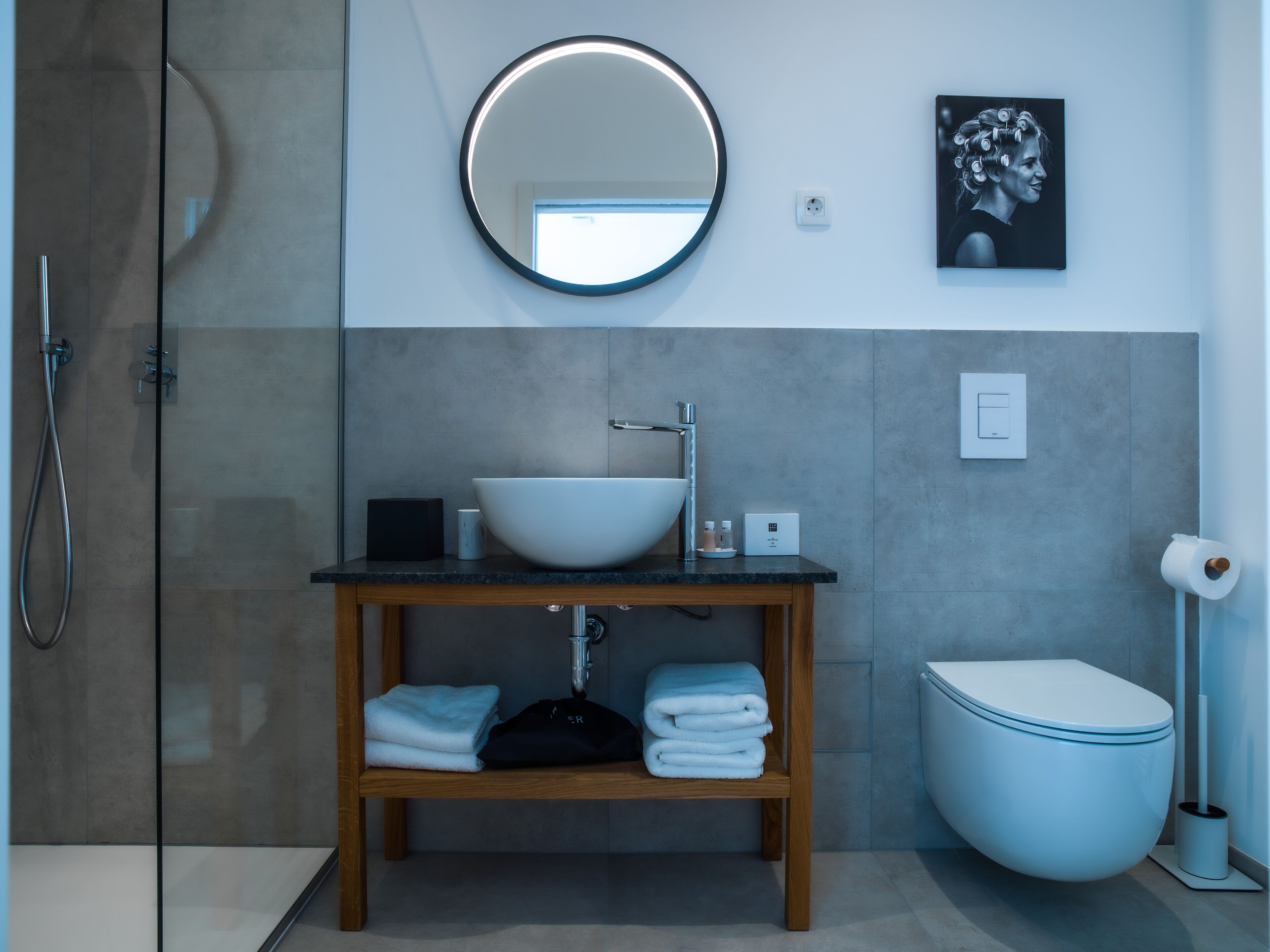 Une salle de bain moderne avec une douche à parois de verre, un meuble-lavabo en bois avec un vasque blanche et des toilettes.