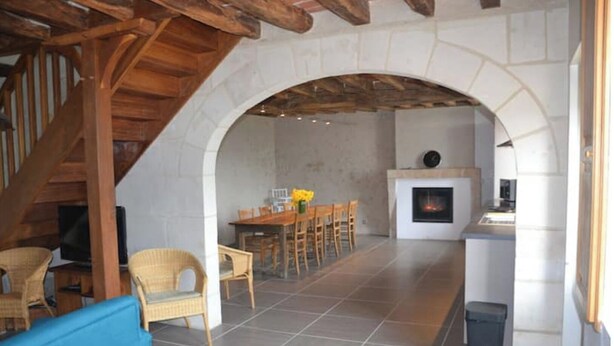 A spacious living area with a stone fireplace, wooden ceiling beams, and a dining area with wicker furniture. - Self catering accomodation CHEZ GERARD, CHAUMONT sur LOIRE, ideal for a family or group of friends (Chaumont sur loire)