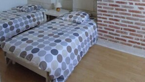 A room with two beds, a small table, a lamp, and a brick-patterned wall. - Self catering accomodation CHEZ GERARD, CHAUMONT sur LOIRE, ideal for a family or group of friends (Chaumont sur loire)