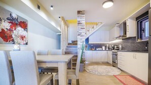 Eine moderne Küche mit weißen Schränken, einem Holzespeisetisch und einer Treppe zu einer oberen Ebene.
