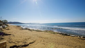 Ein Strand mit blauem Himmel, sandigem Ufer und Blick auf das Meer.