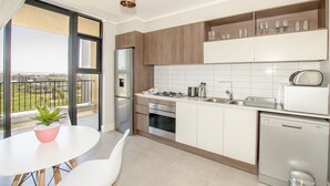 Moderni keittiö, jossa on jääkaappi, uuni, astianpesukone sekä ruokailutila pöytineen ja tuoleineen.