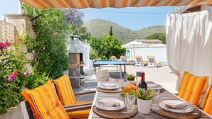 An outdoor dining area with a table set for two, surrounded by striped cushions and a pergola overhead. - Villa Luna with private pool near the beach for 6 persons, AC, WiFi (Alcudia)