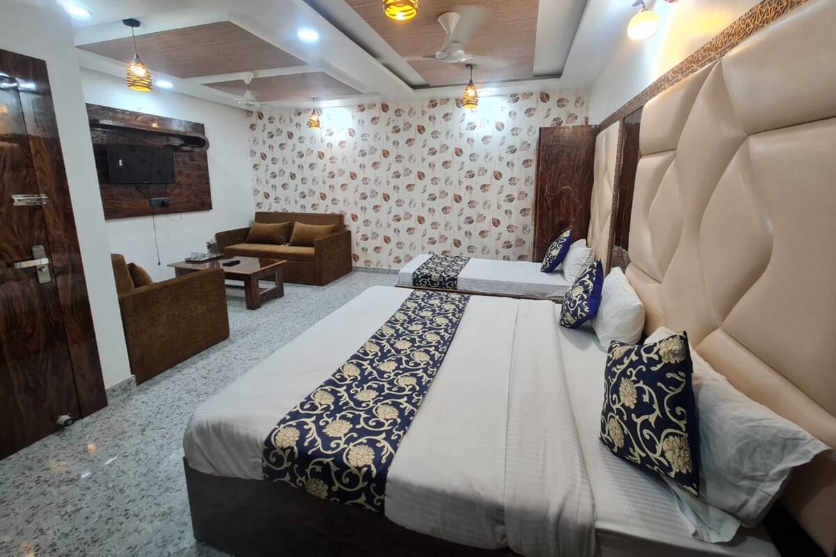 A hotel room with a large bed, a sofa, a TV, and a ceiling fan.