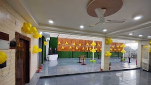 Un espacio interior amplio con piso pulido, ventiladores de techo y globos amarillos.