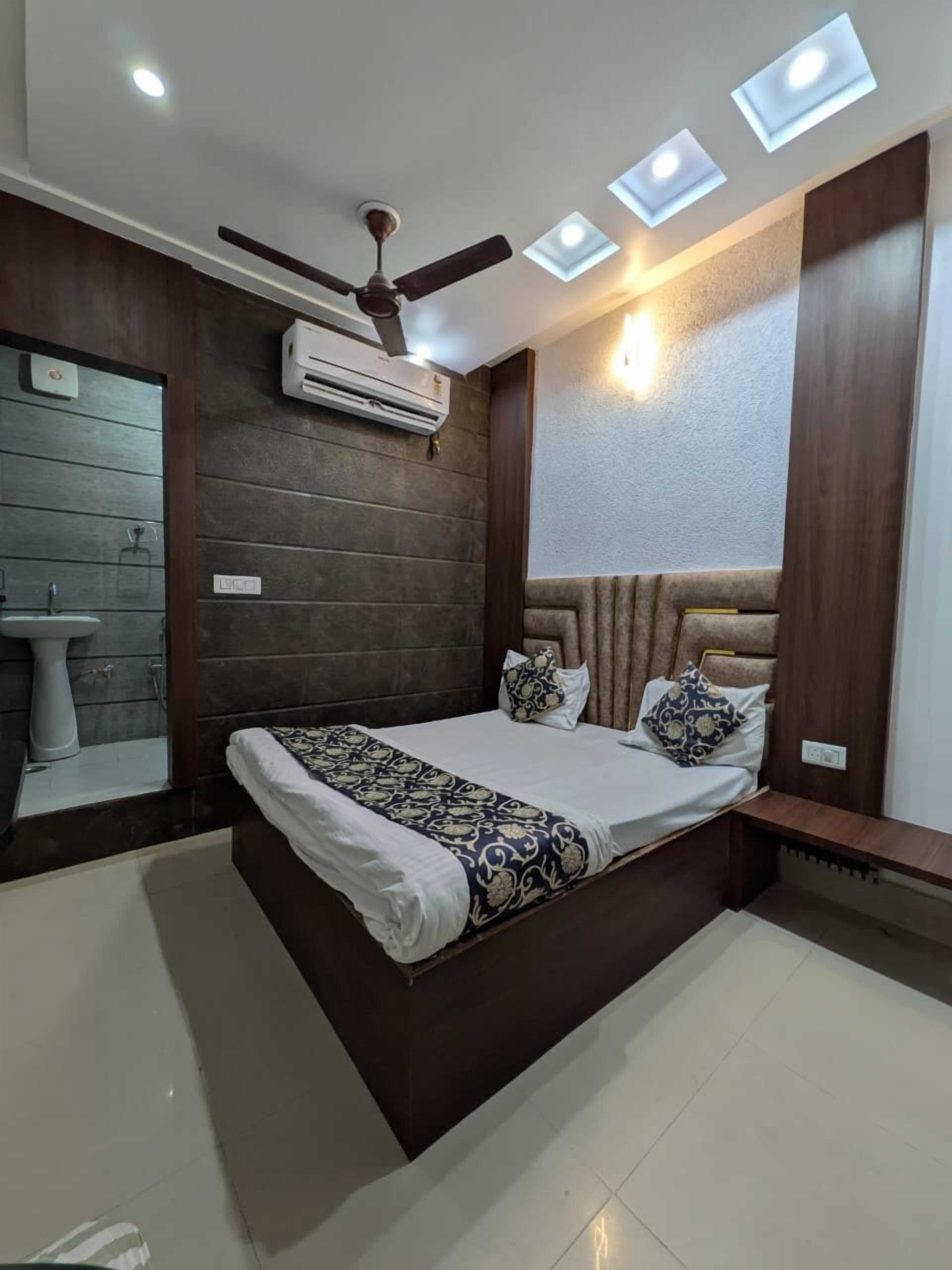 Une chambre moderne équipée d’un lit, d’un ventilateur de plafond, d’un éclairage encastré et d’un appareil de climatisation.