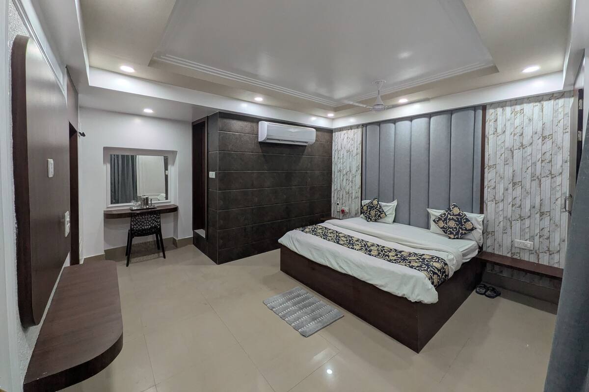 A modern bedroom with a large bed, a desk, and a vanity.