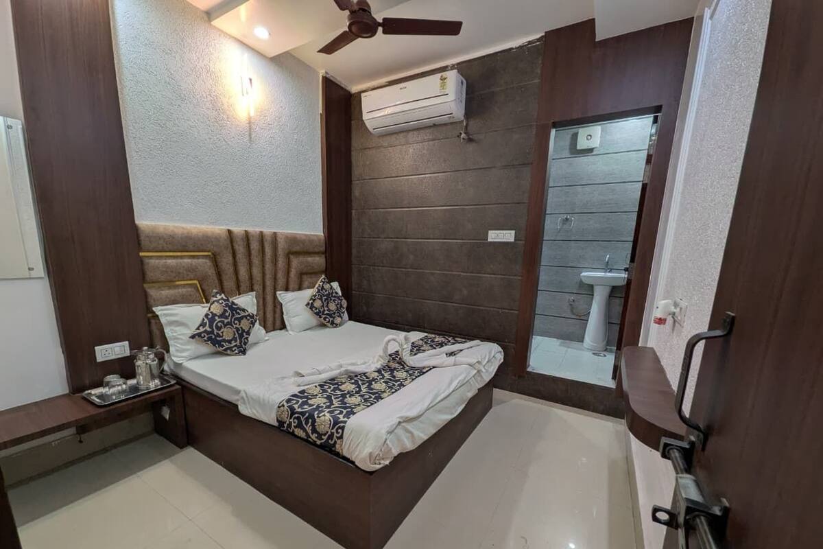 A bedroom with a bed, bedside table, and a view of a bathroom.