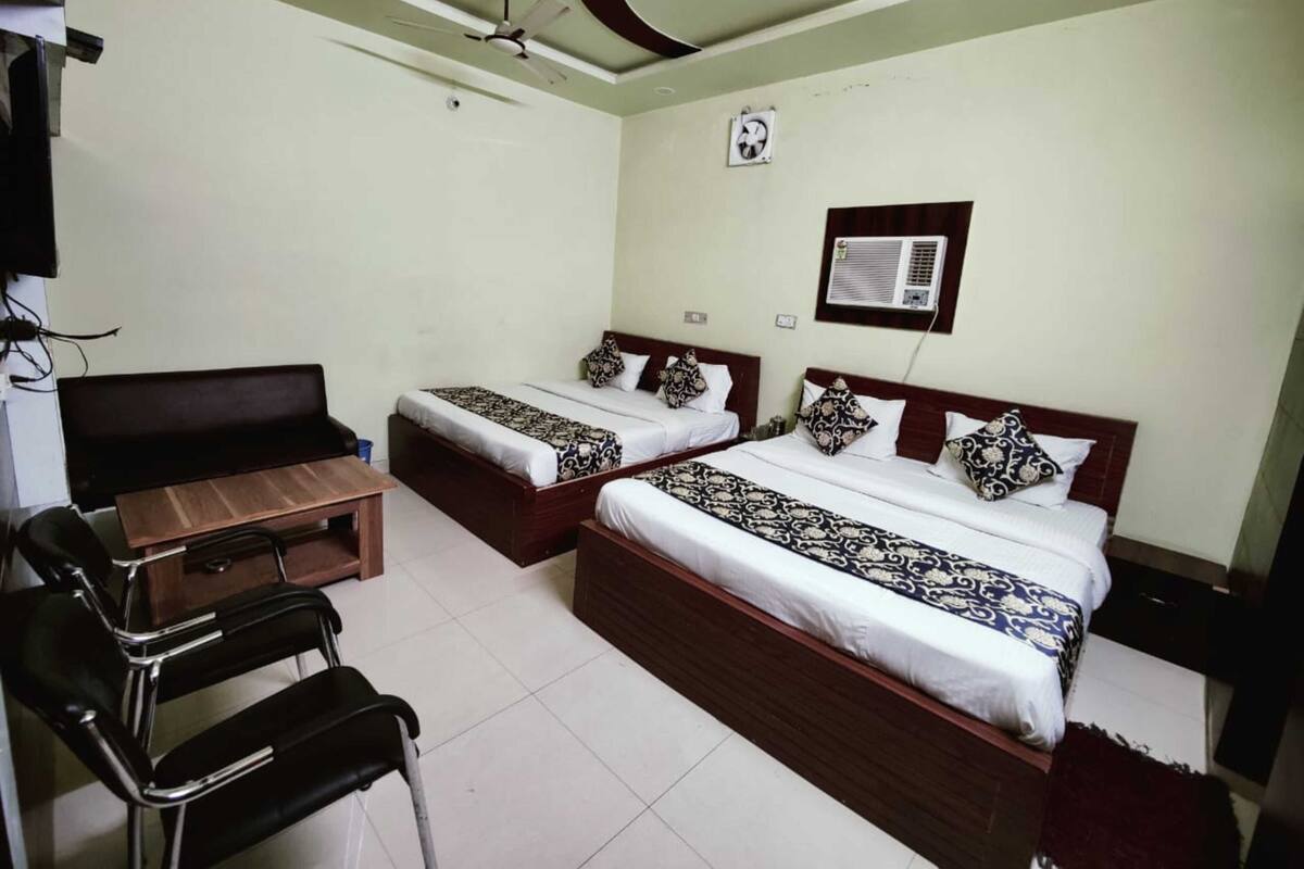 A hotel room with two beds, a desk, a chair, and a ceiling fan.