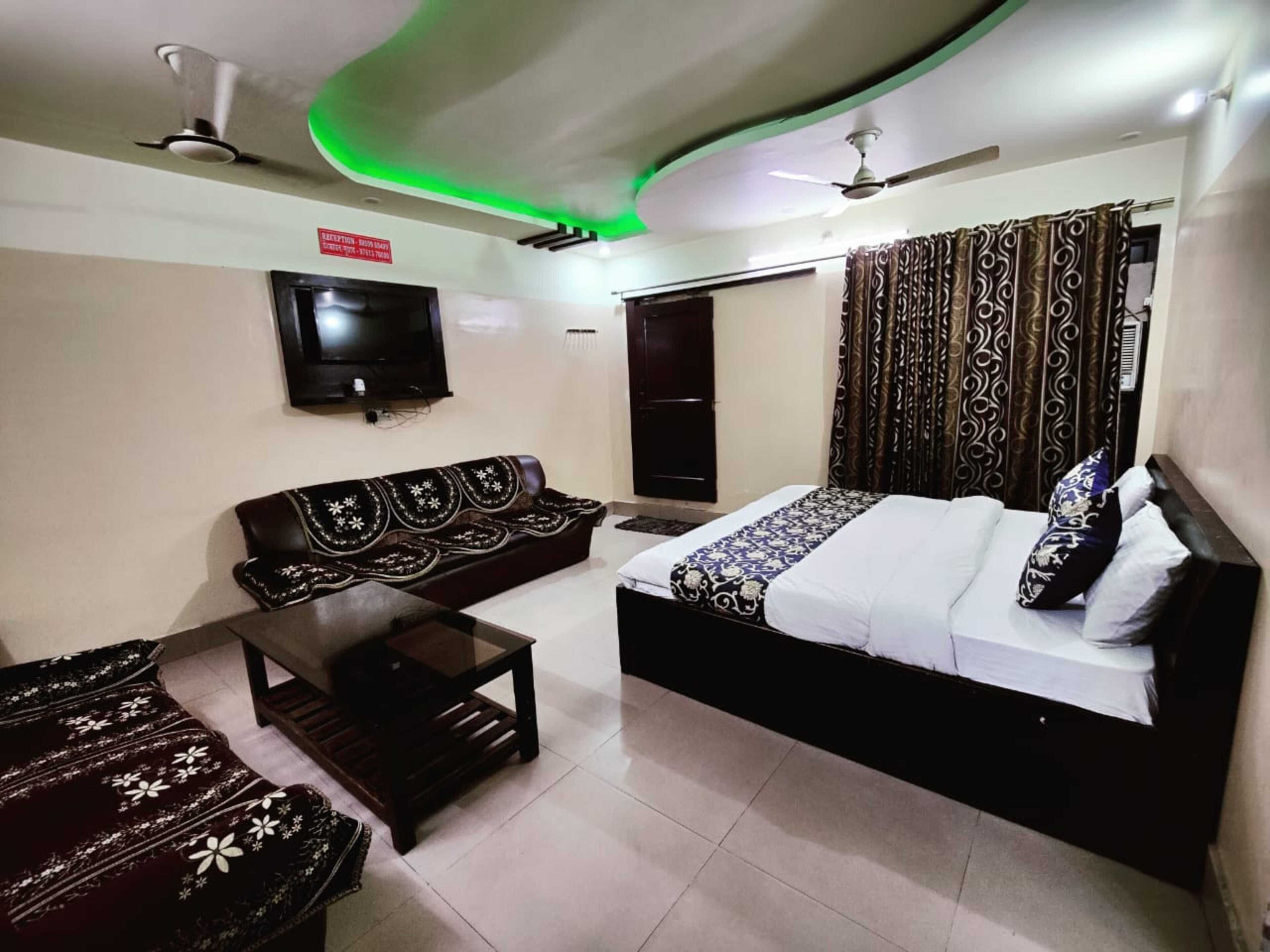 A room with a bed, a sofa, a TV, and a ceiling fan.