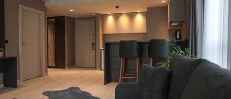 Una sala de estar moderna con sofá, una mesa de centro y una cocina al fondo.