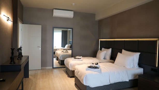 Una habitación de hotel moderna con dos camas, una mesita de noche, un aparador y un espejo.