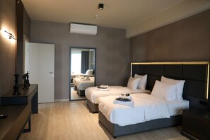 Une chambre d’hôtel moderne avec deux lits, une table de chevet, une commode et un miroir.