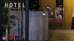 Entrada de un hotel con un mostrador de recepción de mármol, una alfombra roja y un candelabro.