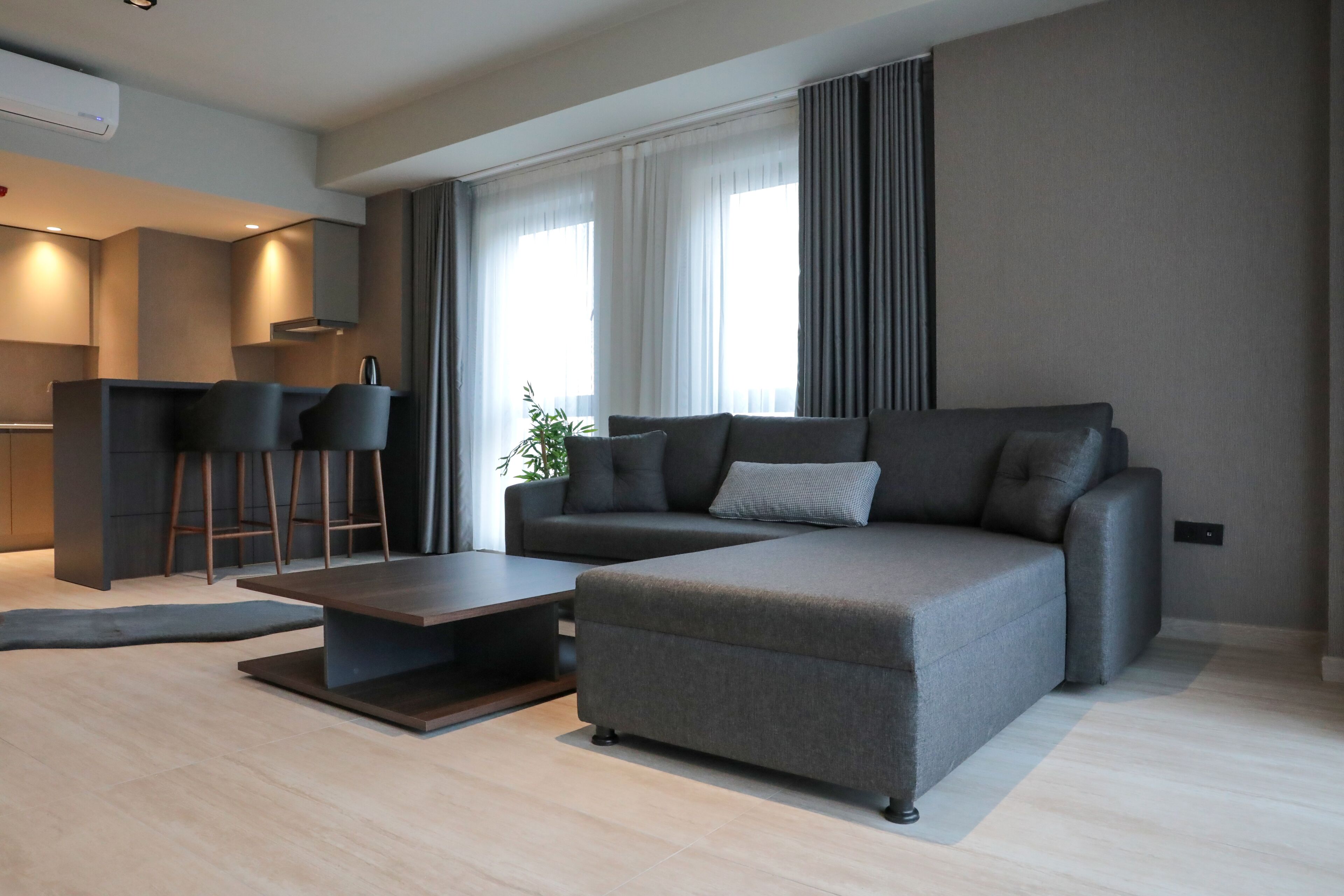 A modern living room with a sectional sofa, a coffee table, and a small bar area with stools.