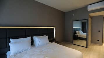 A modern hotel room with a large bed, a headboard, a bedside table, a mirror, and an air conditioning unit.