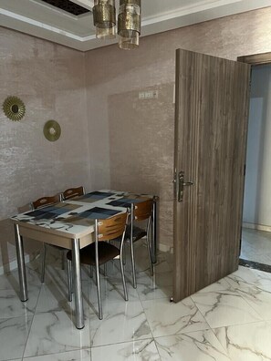Ein Essbereich mit Tisch und Stühlen, einer Holztür und einer Wand mit Muster.
