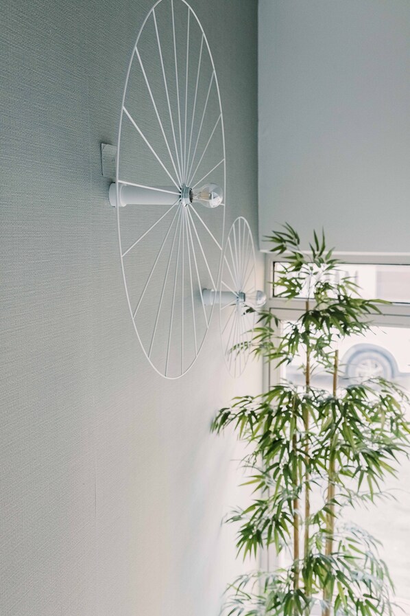 Un luminaire mural au design circulaire, avec un pot de bambou placé à côté.