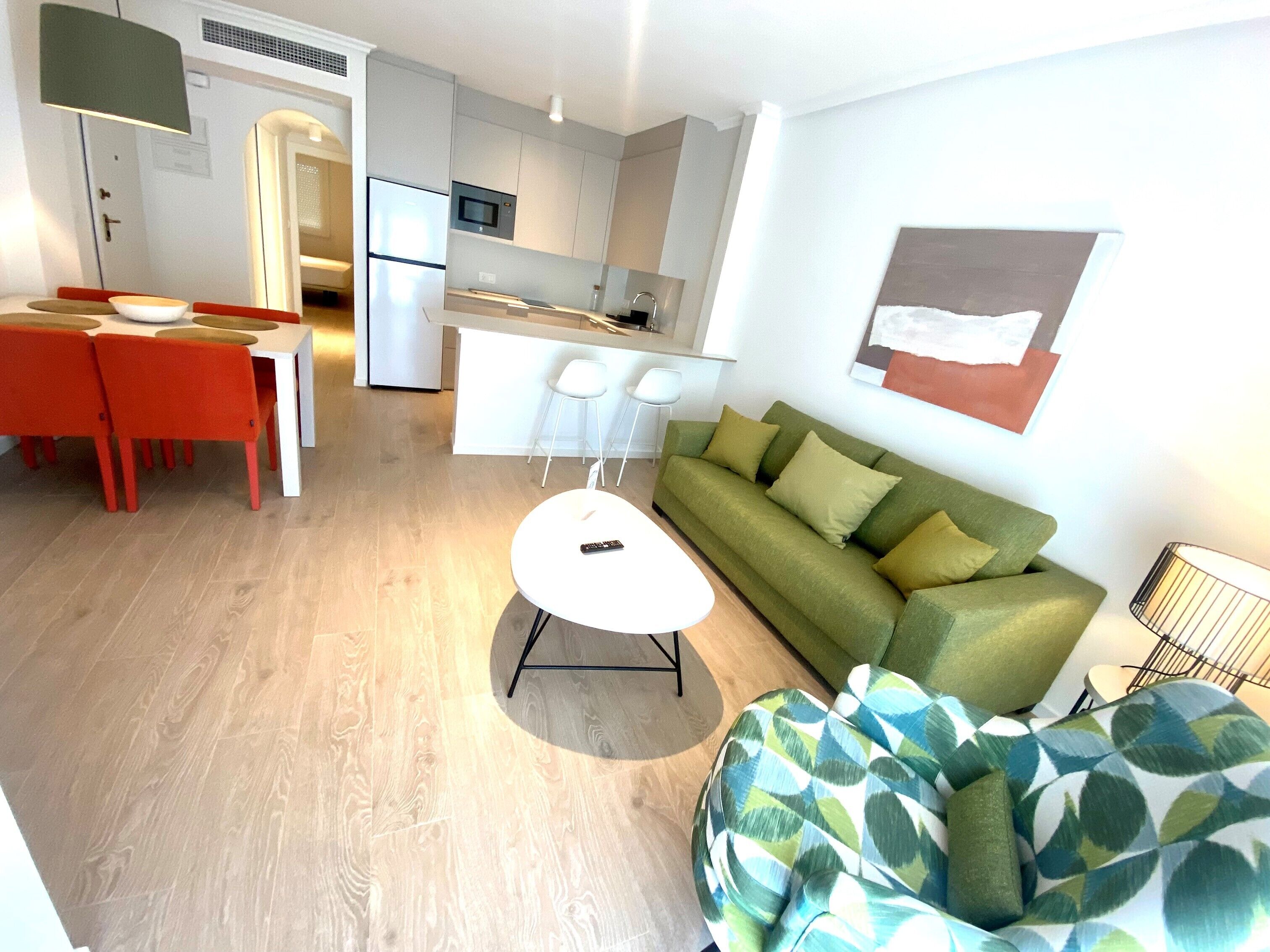 Una sala de estar moderna con un sofá verde, una mesa de centro blanca y un sillón inflable colorido.