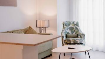 A modern living room with a sofa, a round coffee table, a patterned armchair, and a floor lamp.