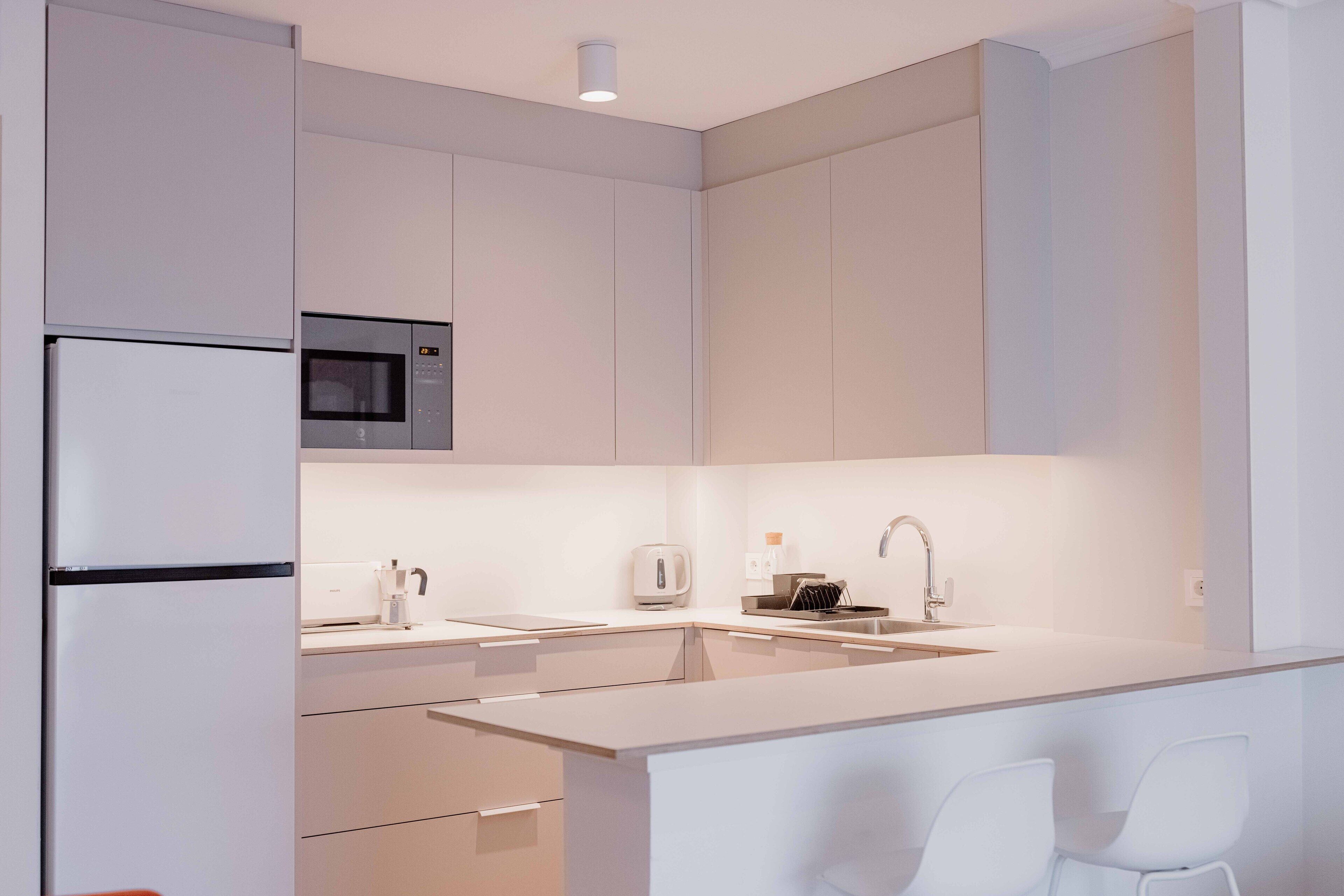 A modern kitchen with a built-in microwave, a sink, and a refrigerator.