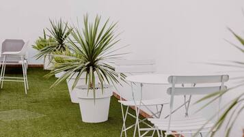 Un espacio interior blanco con césped artificial, muebles blancos y plantas en macetas.