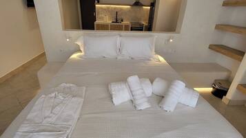 A modern bedroom with a large bed, a built-in archway leading to a kitchen, and a wooden staircase.