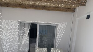 Pátio ensolarado com duas cadeiras de descanso e uma porta de vidro deslizante que dá para um quarto.