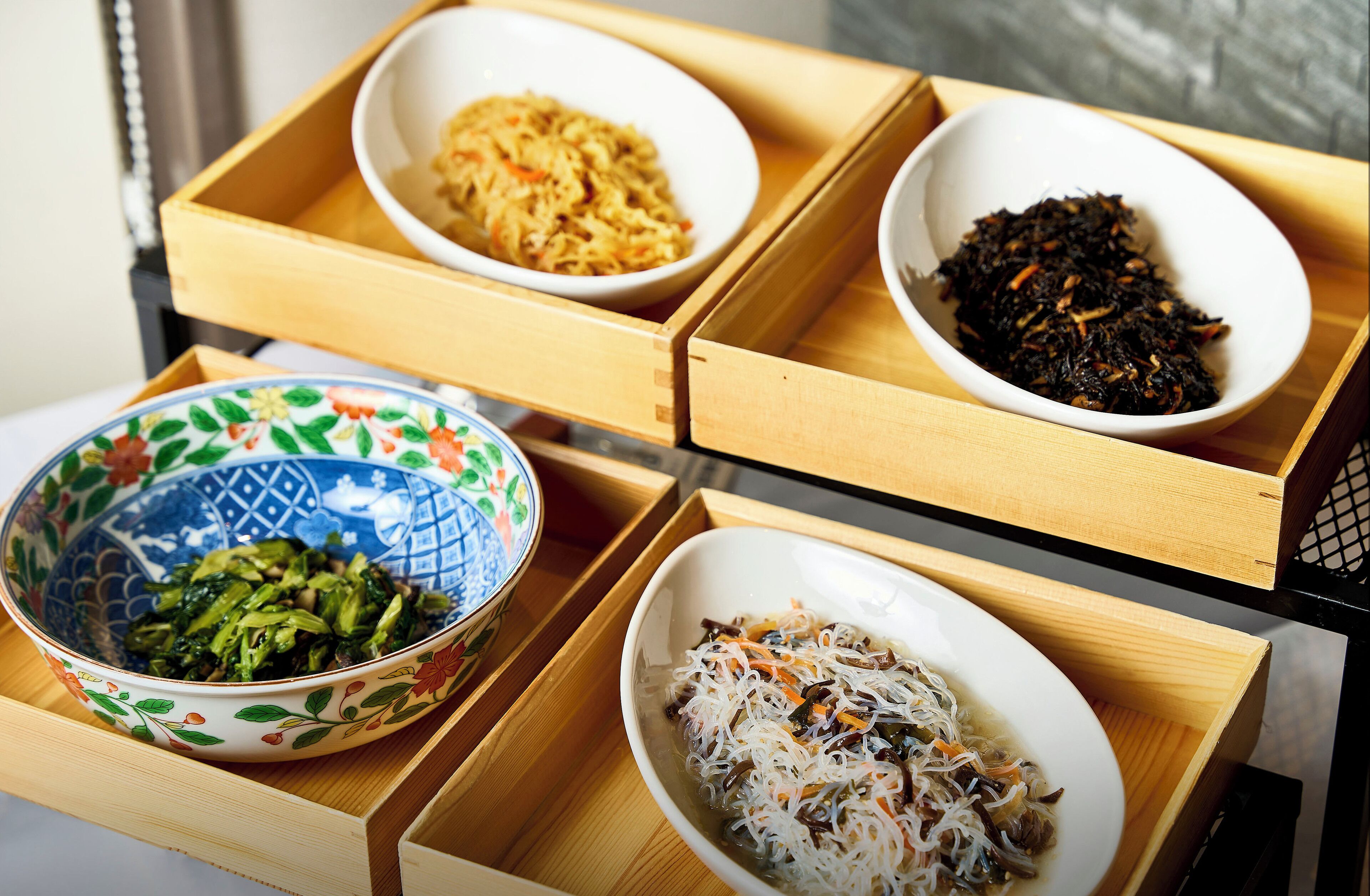 A wooden tray with four bowls containing different dishes.