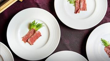 A table with white plates, each with a piece of meat and a green garnish.