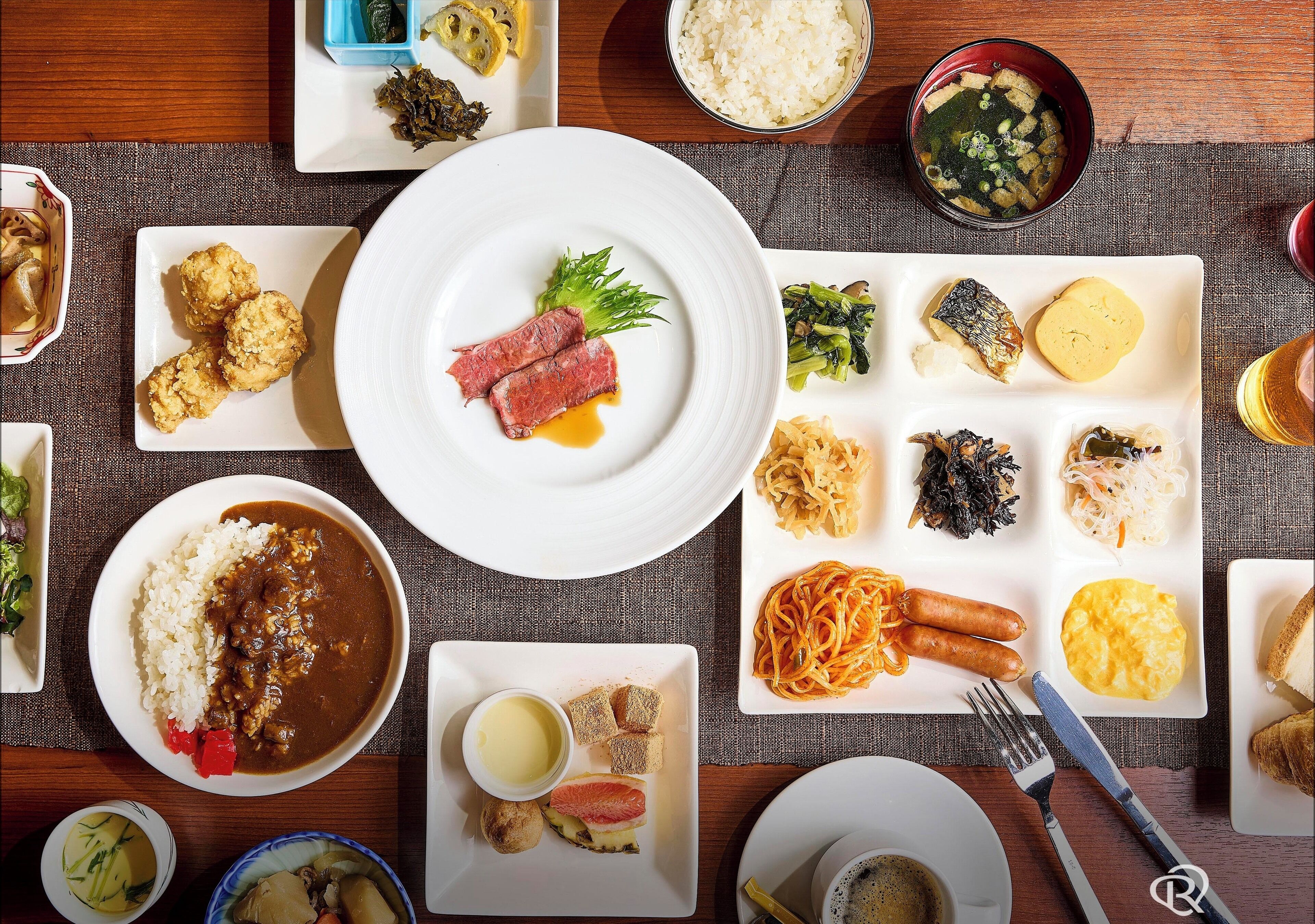 A variety of dishes on a table, including rice, meat, vegetables, and noodles.