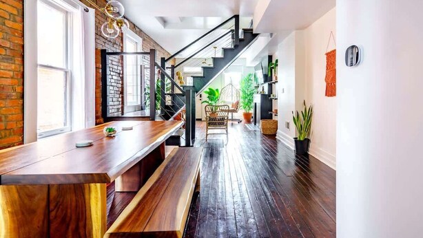 A modern interior with a wooden bench, a staircase, and potted plants.